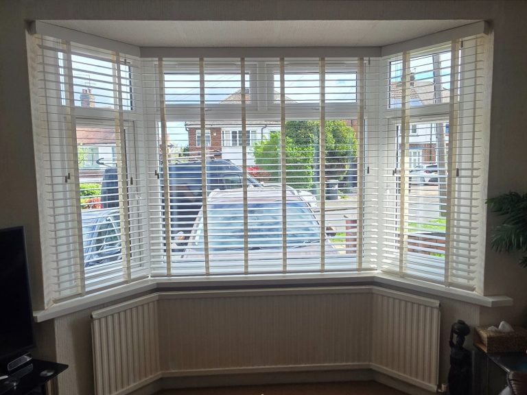 Wooden taped venetian blinds expertly installed into a bay window recess