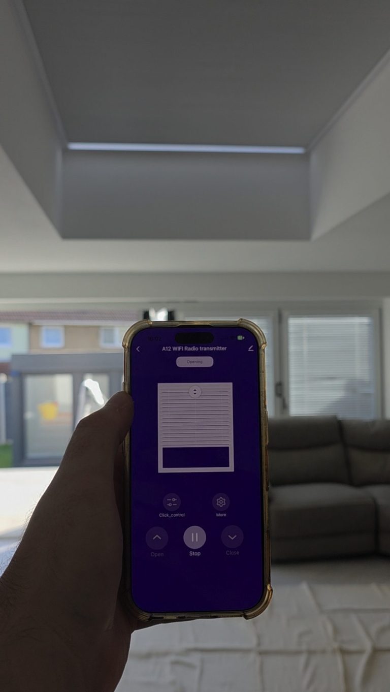 Solar powered roof lantern blind fully extended above a living room, with smart app controls displayed on a smartphone in Corby, Northampton