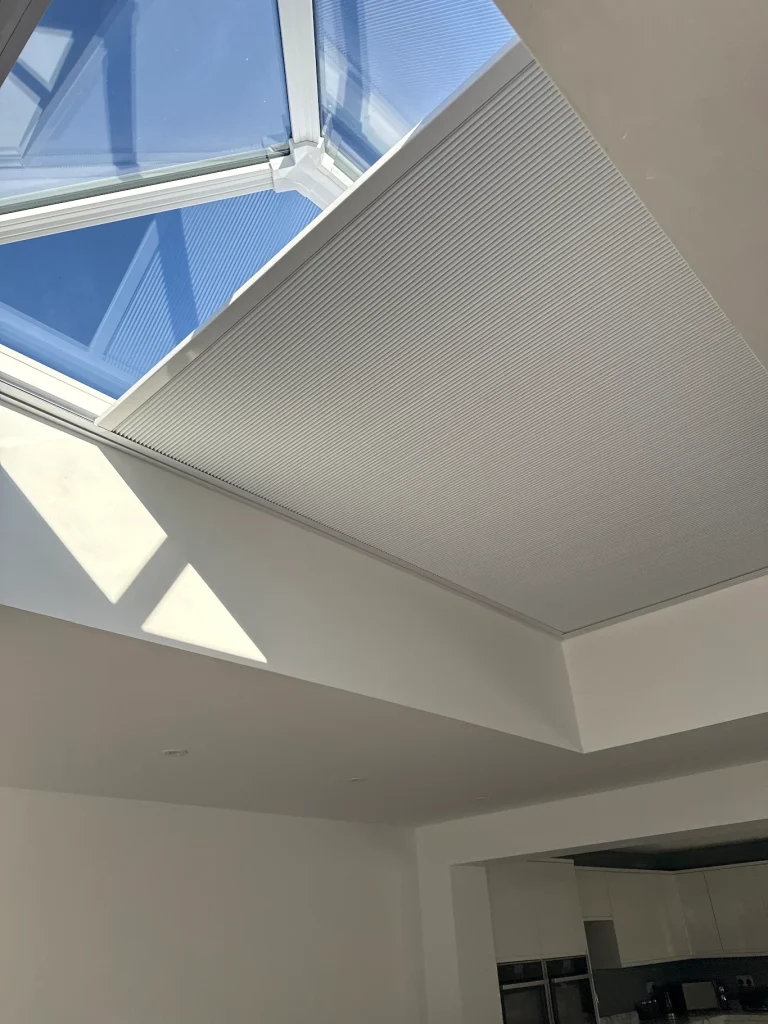 Made-to-measure solar powered roof lantern blind partially extended to reduce sunlight and glare in a home in Corby, Northamptonshire.