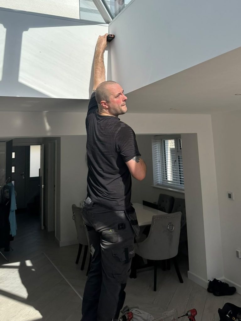 Rhys from TrueShade Interiors installing a solar powered, smart controlled roof lantern blind in a home in Corby, Northamptonshire.