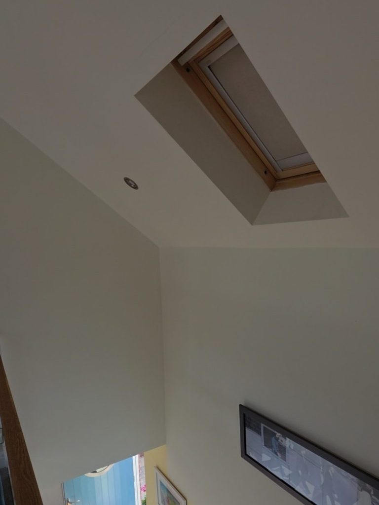 Solar powered VELUX blind fitted to a high-level roof window in a sloping ceiling in Great Oxendon, Northamptonshire