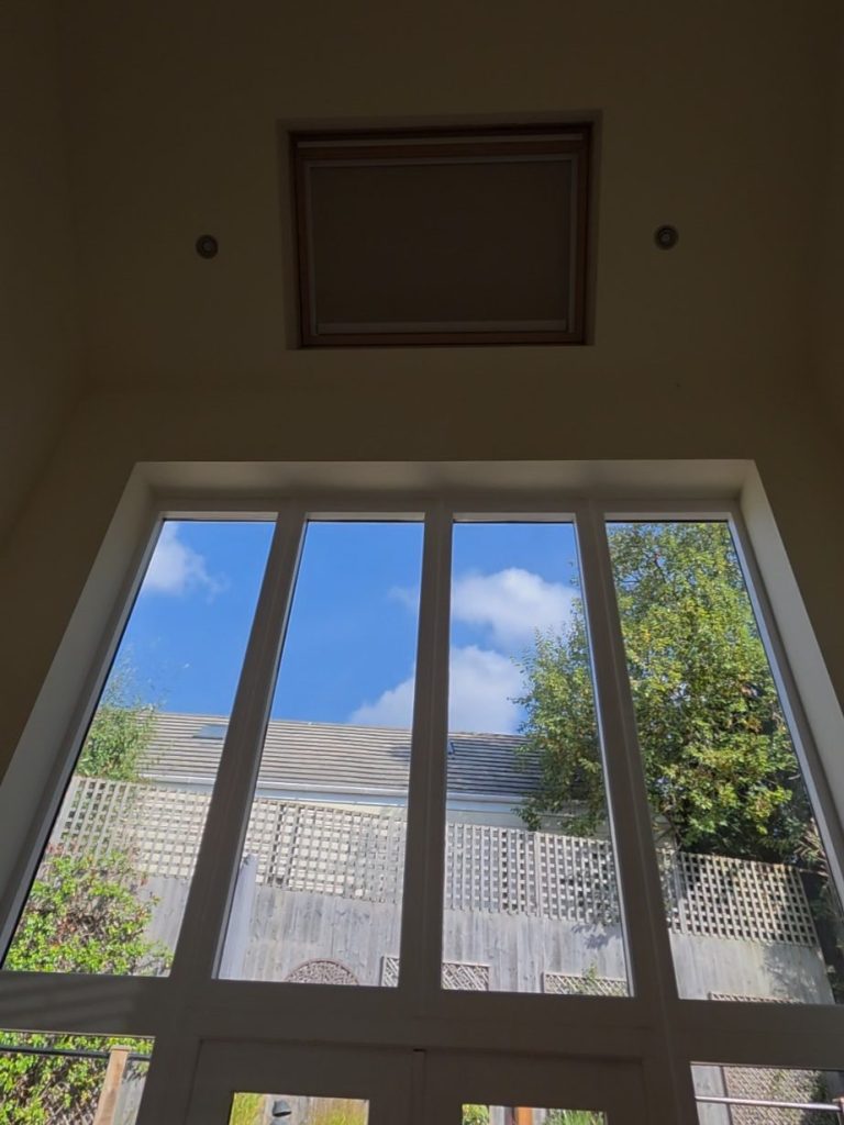 Solar powered VELUX blind installed in a high-level roof window above tall glazing in Great Oxendon, Northamptonshire