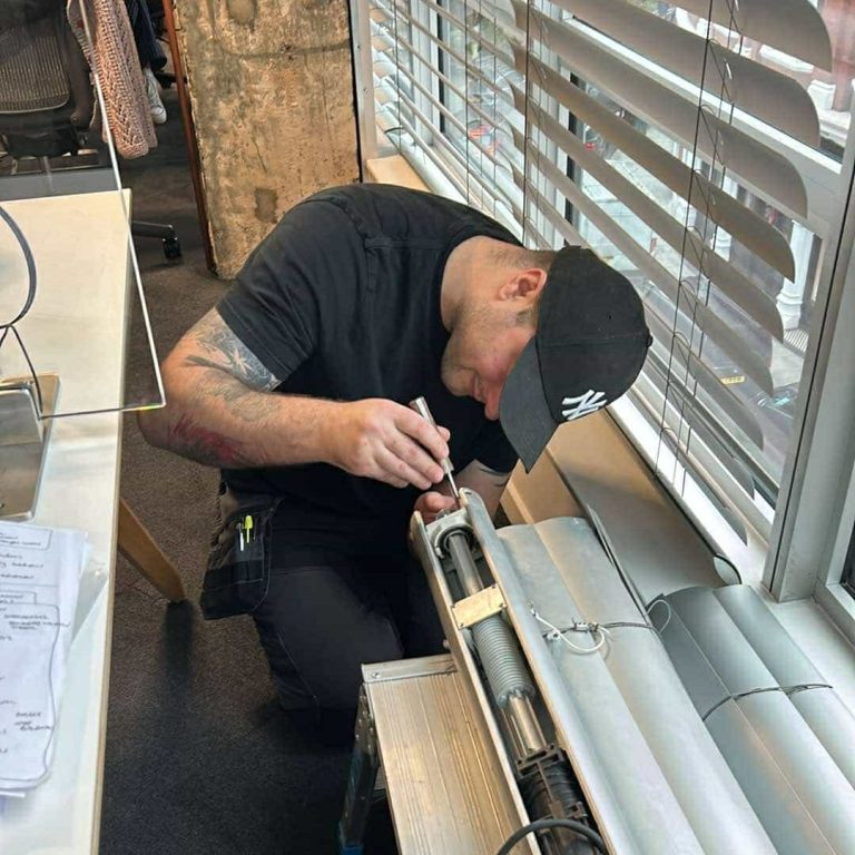 Venetian Blind Installation | TrueShade Interiors Rhys from TrueShade Interiors working on a motorised Venetian blind mechanism beside a window